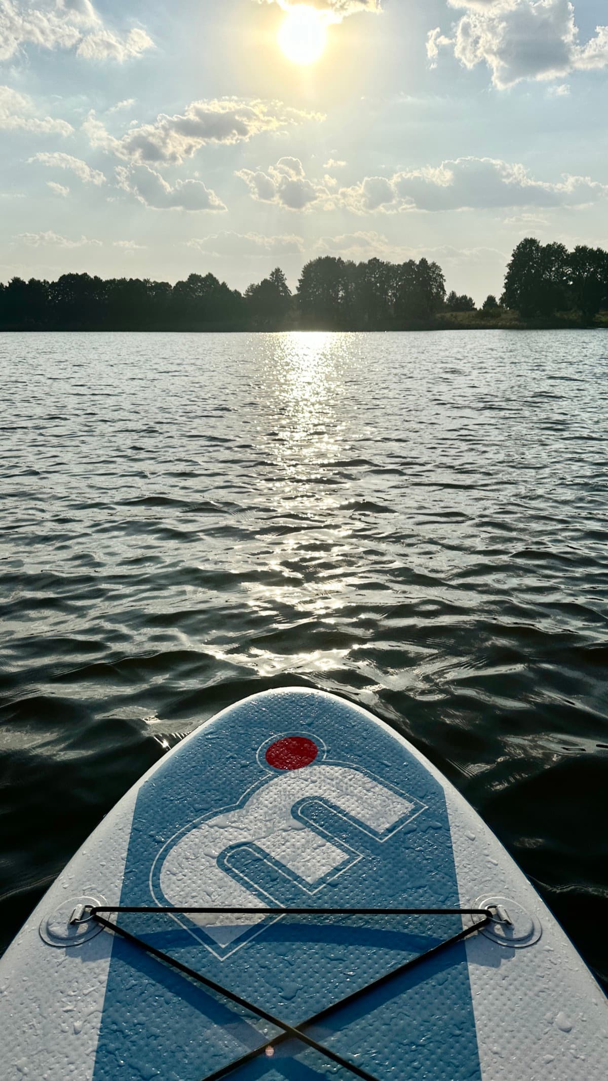 Widok z deski SUP na jezioro w zachodzącym słońcu