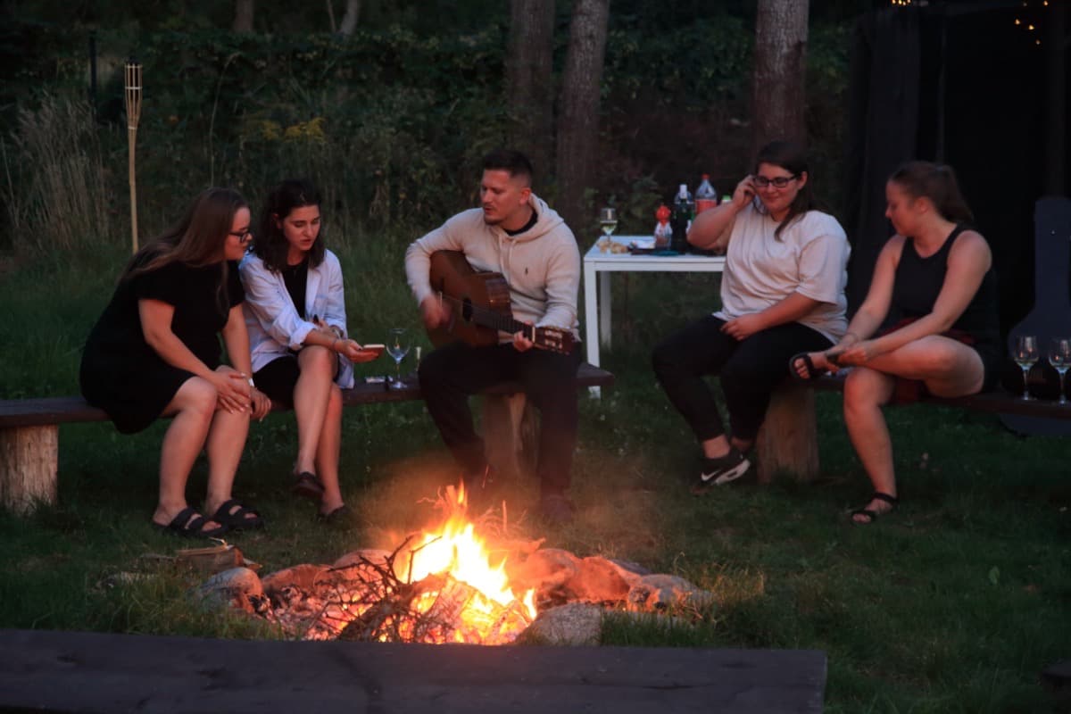 Wieczorna biesiada przy ognisku z drewnianymi siedziskami