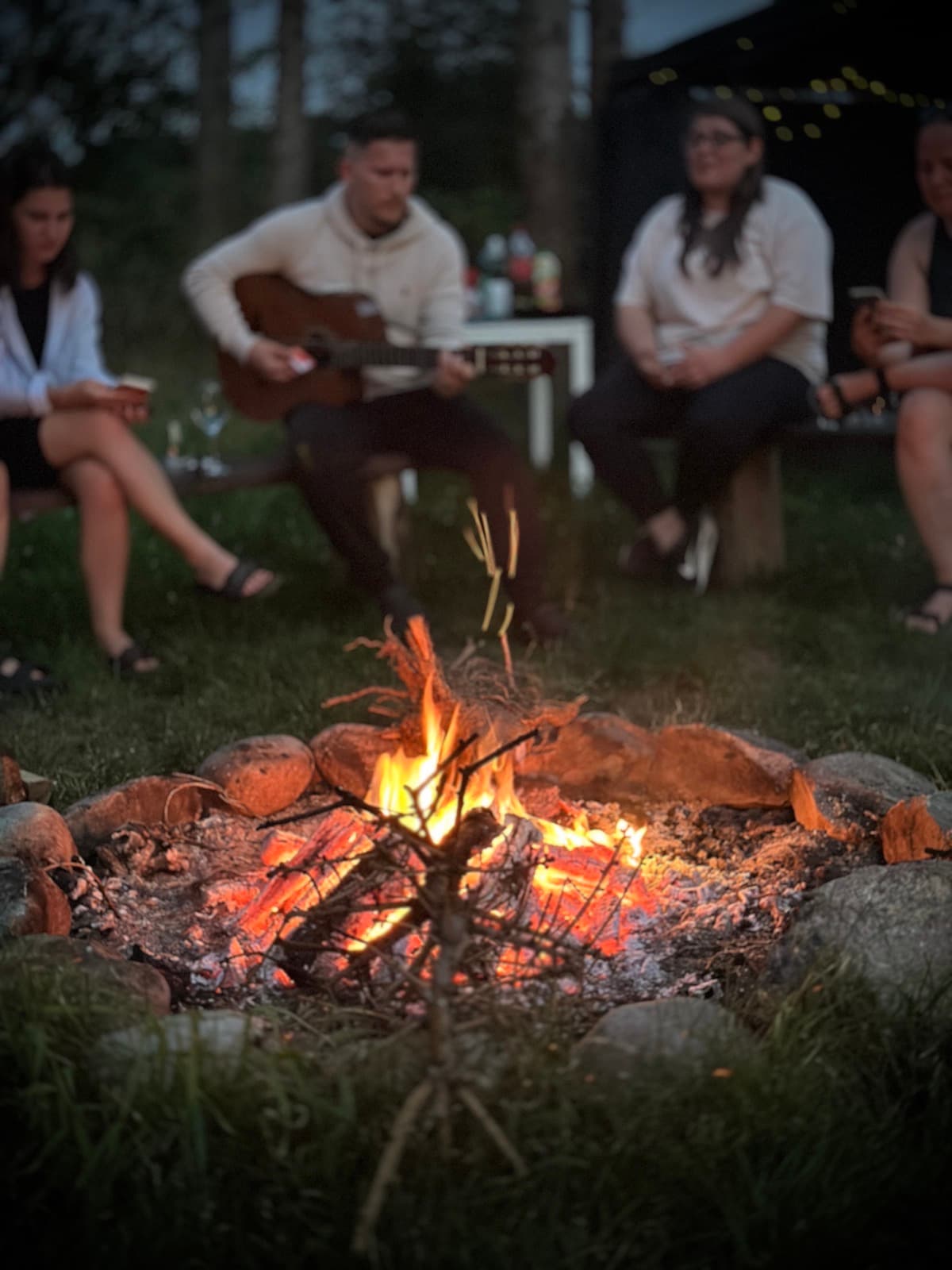 Wieczorne ognisko z gitarzystą i grupą wokół ognia