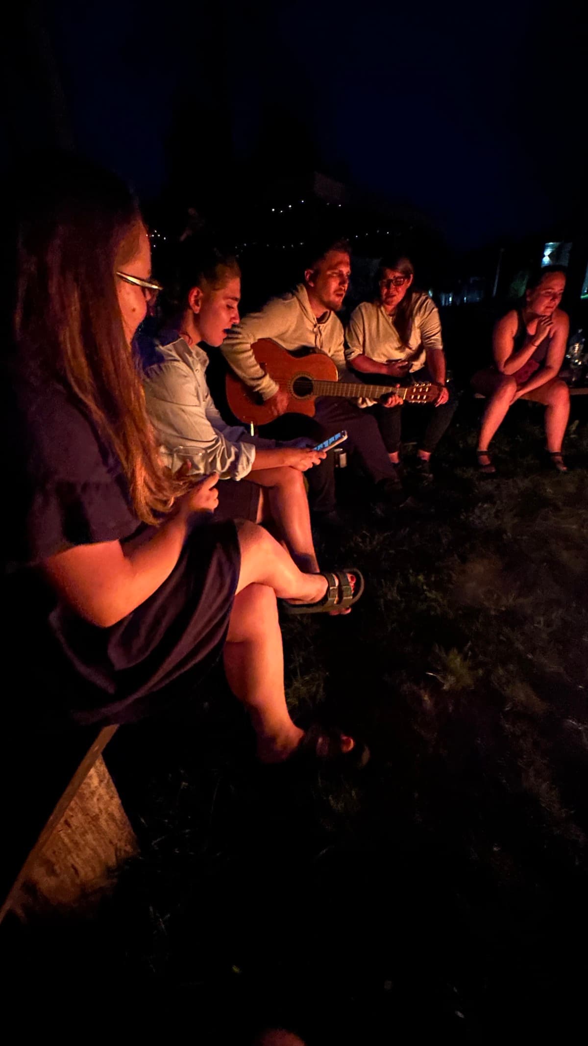 Ognisko o zmierzchu z lampkami i grupą przyjaciół