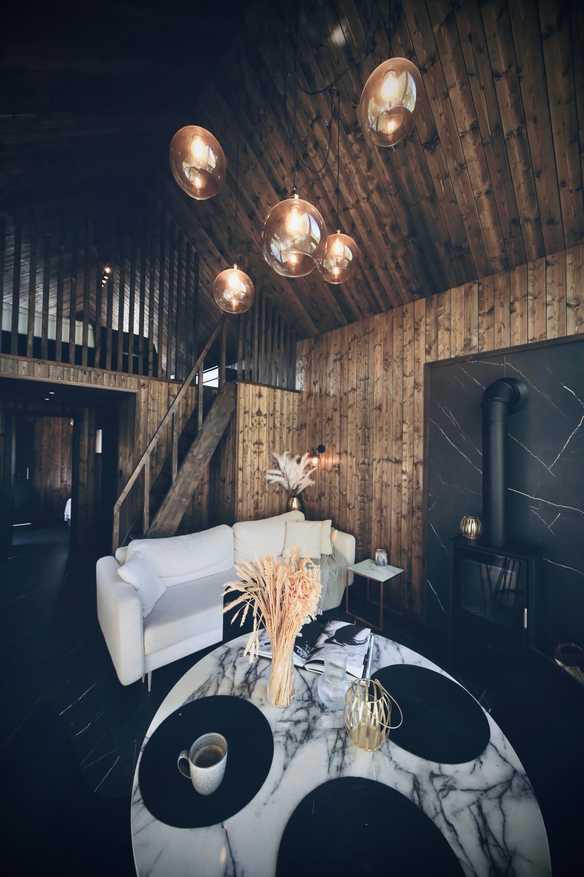 Salon z kominkiem, antresolą i bursztynowymi lampami